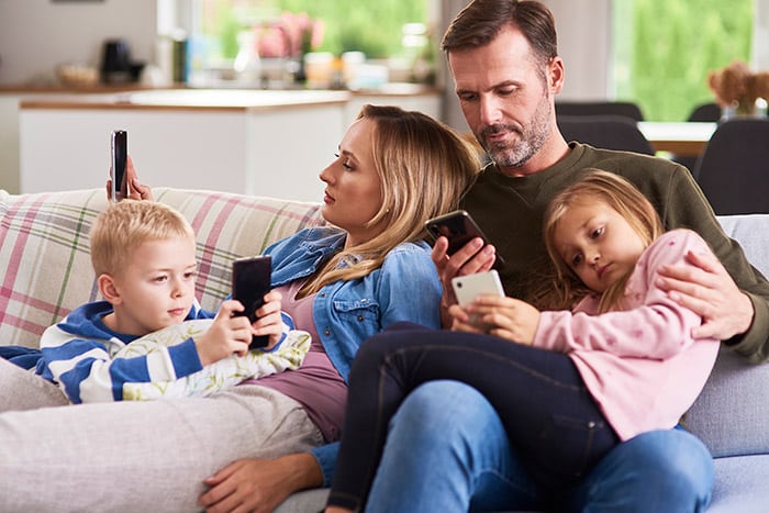 parents-children-using-mobile-phone-living-room